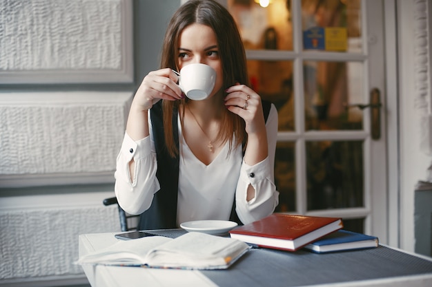 stylish young businesswoman sitting in a cafe with notebook and drinking a coffee