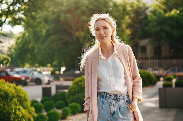 Stylish young businesswoman walking on the city street on sunny day