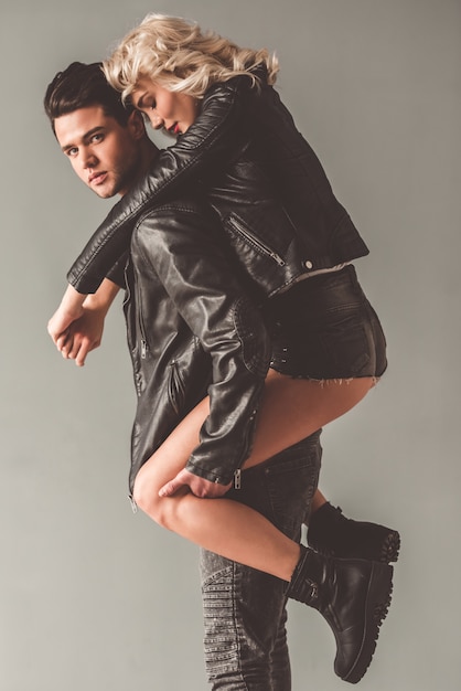 Stylish young couple in leather jackets on gray background