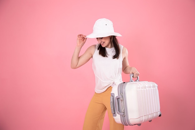 Stylish young girl in a hat with a suitcase. Summer vacation and travel concept copy space.