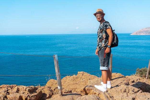 Stylish young guy on the cliff by the sea