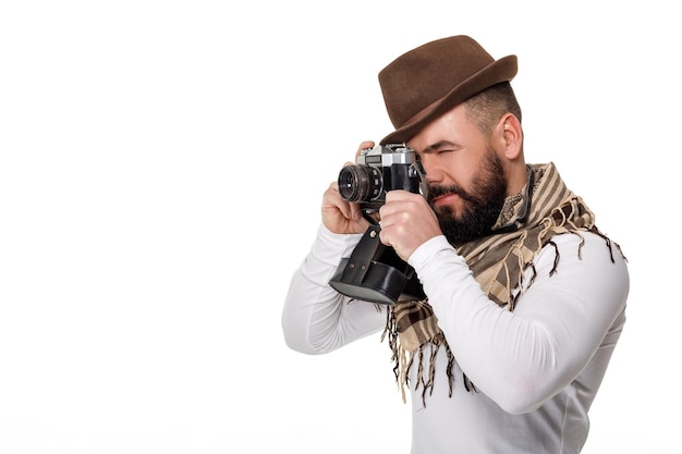 Stylish young male photographer with retro camera takes photos on white background