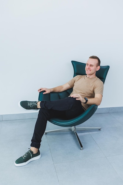 Stylish young man in a beige tshirt and black trousers a man in green leather casual sneakers