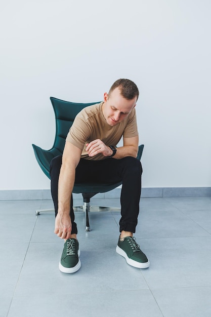 Stylish young man in a beige tshirt and black trousers a man in green leather casual sneakers