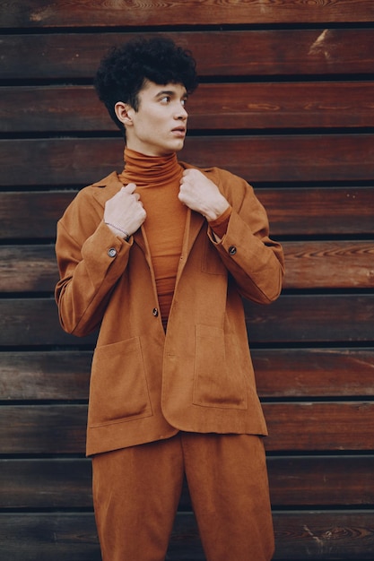 Stylish young man in brown suit against a wooden background