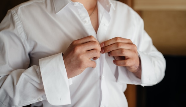 Stylish young man buttoning the cuff links on the sleeves. Style.