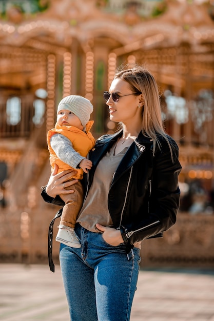 Stylish young mom walks with the baby in the park. Happy Mom