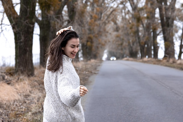 Stylish young woman by the asphalt road in the cold season