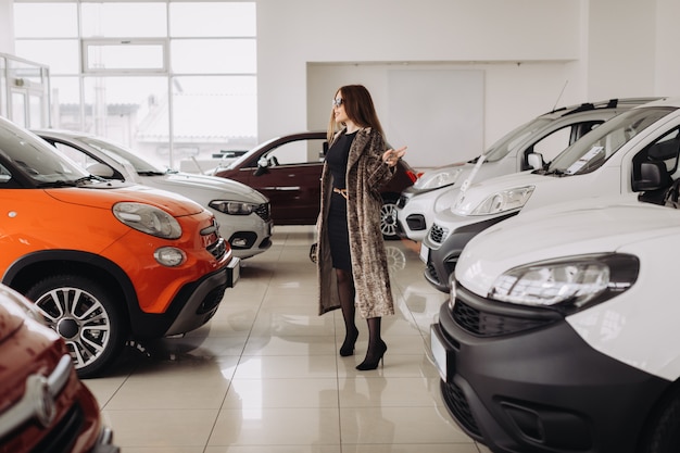 A stylish young woman is choosing a new car in a car store