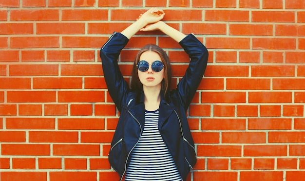 stylish young woman model wearing black leather jacket in rock style on city street