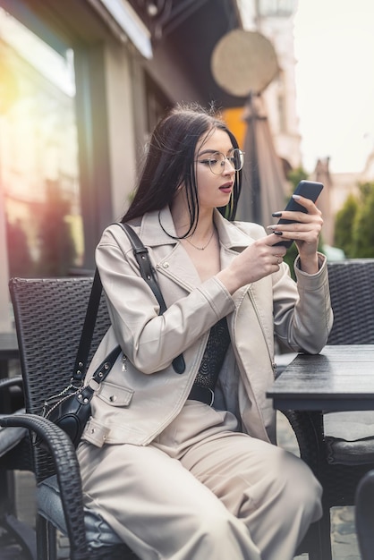 Stylish young woman sitting at a table and working on the phone