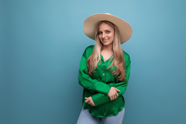 Stylish young woman in summer hat with brim on blue background