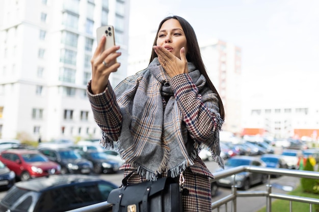 Stylish young woman talking on video call outside