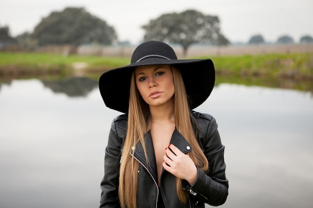 Stylish young woman with beautiful hat in the field