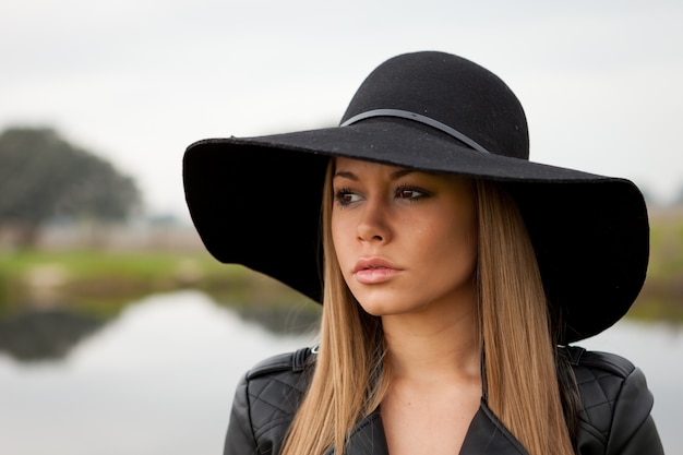 Stylish young woman with beautiful hat in the field