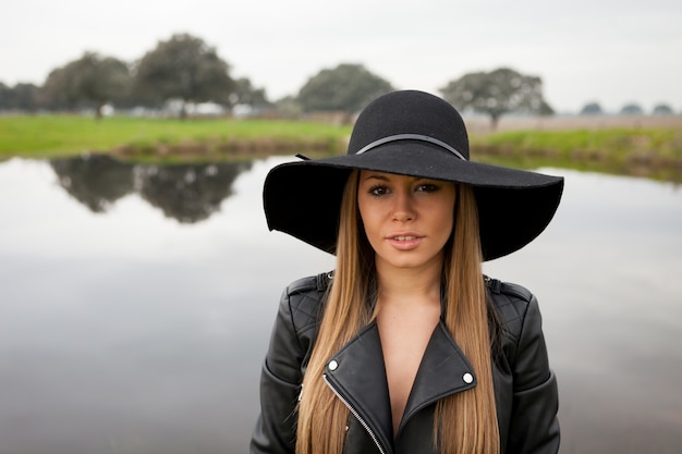 Stylish young woman with beautiful hat in the field