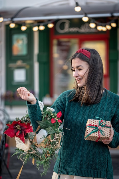 Stylish young woman with a christmas wreath in red and green colors