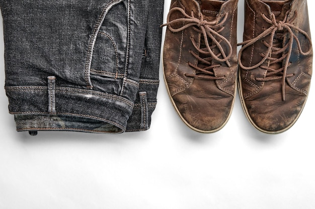 Stylishly distressed vintage brown leather shoes and black jeans isolated on white background