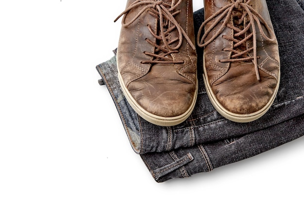 Stylishly distressed vintage brown leather shoes and black jeans isolated on white background