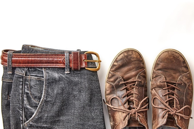 Stylishly distressed vintage brown leather shoes and black jeans isolated on white background