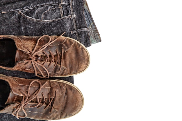 Stylishly shabby vintage brown leather shoes and black jeans on a white background