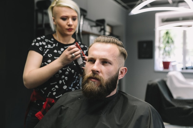 The stylist keeps the mustache of the brutal bearded man in the barber shop.