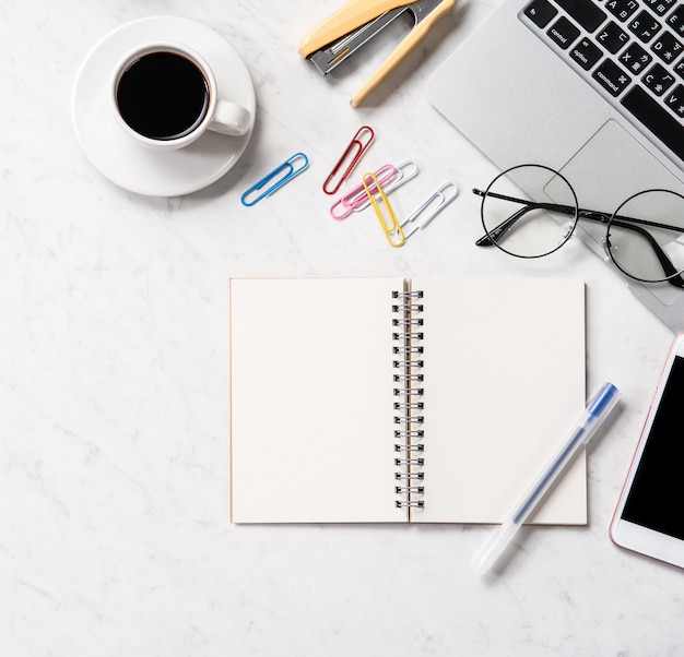 Stylized marble office working desk with smartphone, laptop, glasses and coffee