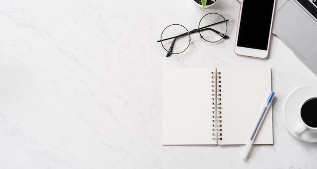 Stylized marble office working desk with smartphone, laptop, glasses and coffee