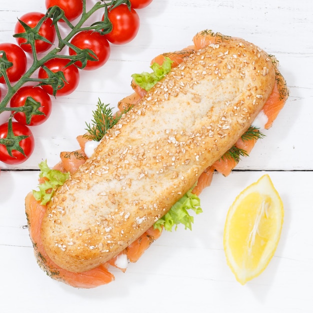 Sub sandwich whole grain grains baguette with salmon fish square from above on wooden board