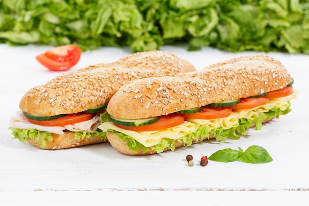 Sub sandwiches whole grain grains baguettes with ham and cheese on wooden board