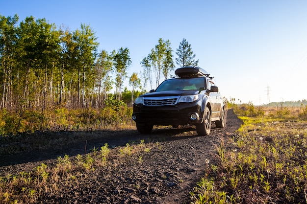 Subaru Forester with roof box at dirt road in the forest