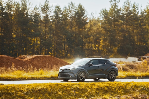 A subcompact SUV car explores the scenic countryside with a stunning sunset and alpine mountains in the background