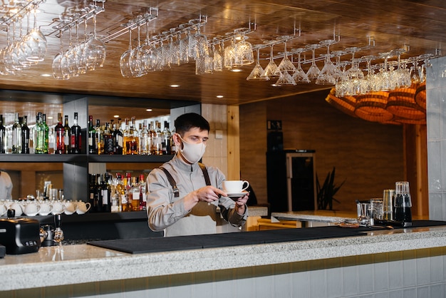 Submission of a Barista in a mask of delicious organic coffee in modern cafe during the pandemic.