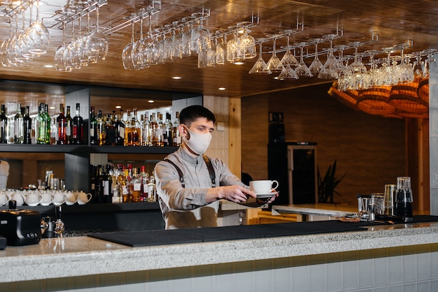 Submission of a Barista in a mask of delicious organic coffee in modern cafe during the pandemic