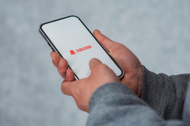 Subscribe to the Internet channel on the smartphone display. Man holds smartphone close-up with icon.