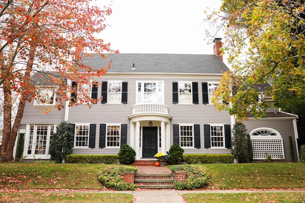 suburban house framed by a white picket fence symbolizing the American dream faces the skyward tre