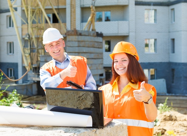 Success female and male construction workers   with a laptop and drawings