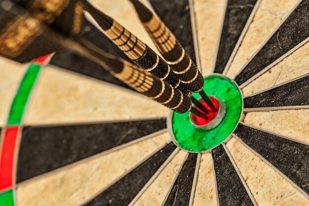 Success hitting target aim goal achievement concept background three darts in bull's eye close up