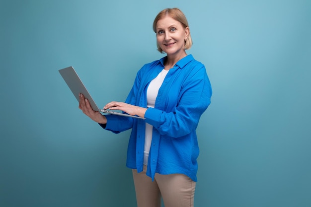 Successful adult business woman learns a profession remotely using a laptop on a blue background