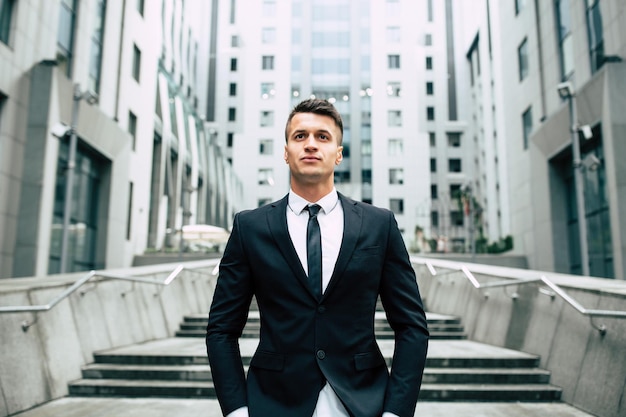 Successful and advanced handsome business man in a suit looks up in front of him standing on the background of concrete steps