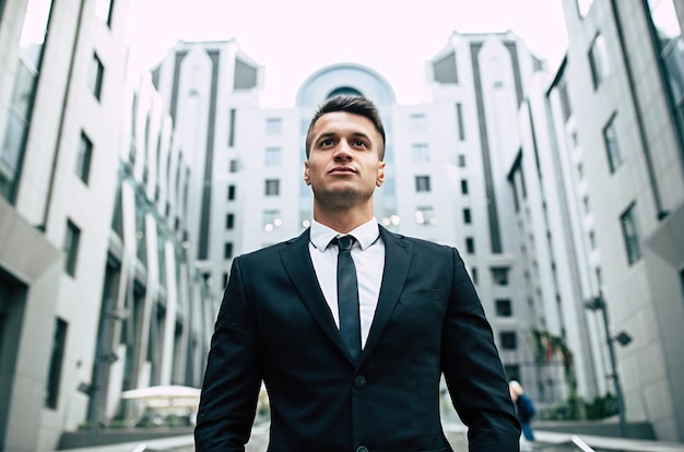 Successful and advanced handsome business man in a suit looks up in front of him standing on the background of concrete steps