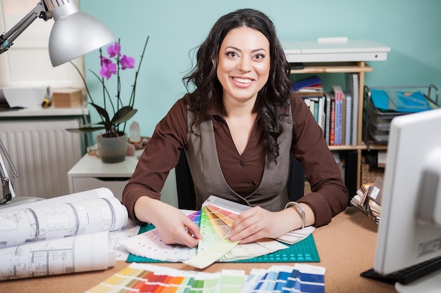 Successful architect woman in her office with color cards in front of her. Architecture and construction. Color pallete