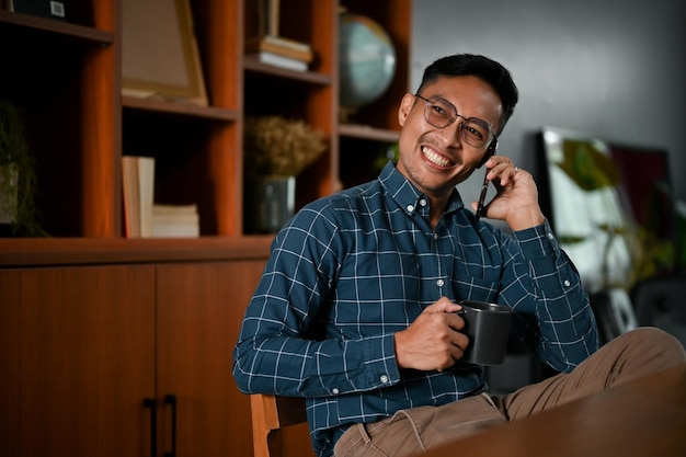 Successful Asian businessman talking on the phone with his business partner in his office