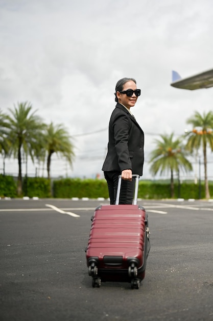 A successful Asian businesswoman with her luggage is boarding a plane for a business trip