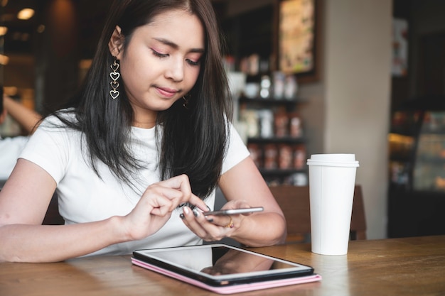 Successful asian woman using smartphone for online business at coffee cafe.