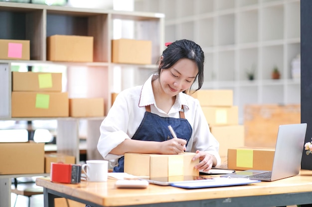 Successful Asian women entrepreneur with parcel boxes in her own job shopping online business at home office start up small business sme concept