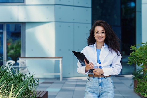 Successful beautiful business woman in suit with document walking to the meeting near modern office