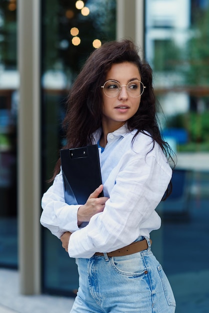 Successful beautiful business woman in suit with document walking to the meeting near modern office