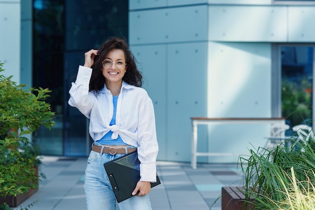 Successful beautiful business woman in suit with document walking to the meeting near modern office