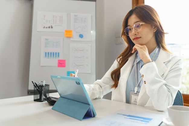 Successful business concept Businesswoman resting chin on hand and writing data on tablet